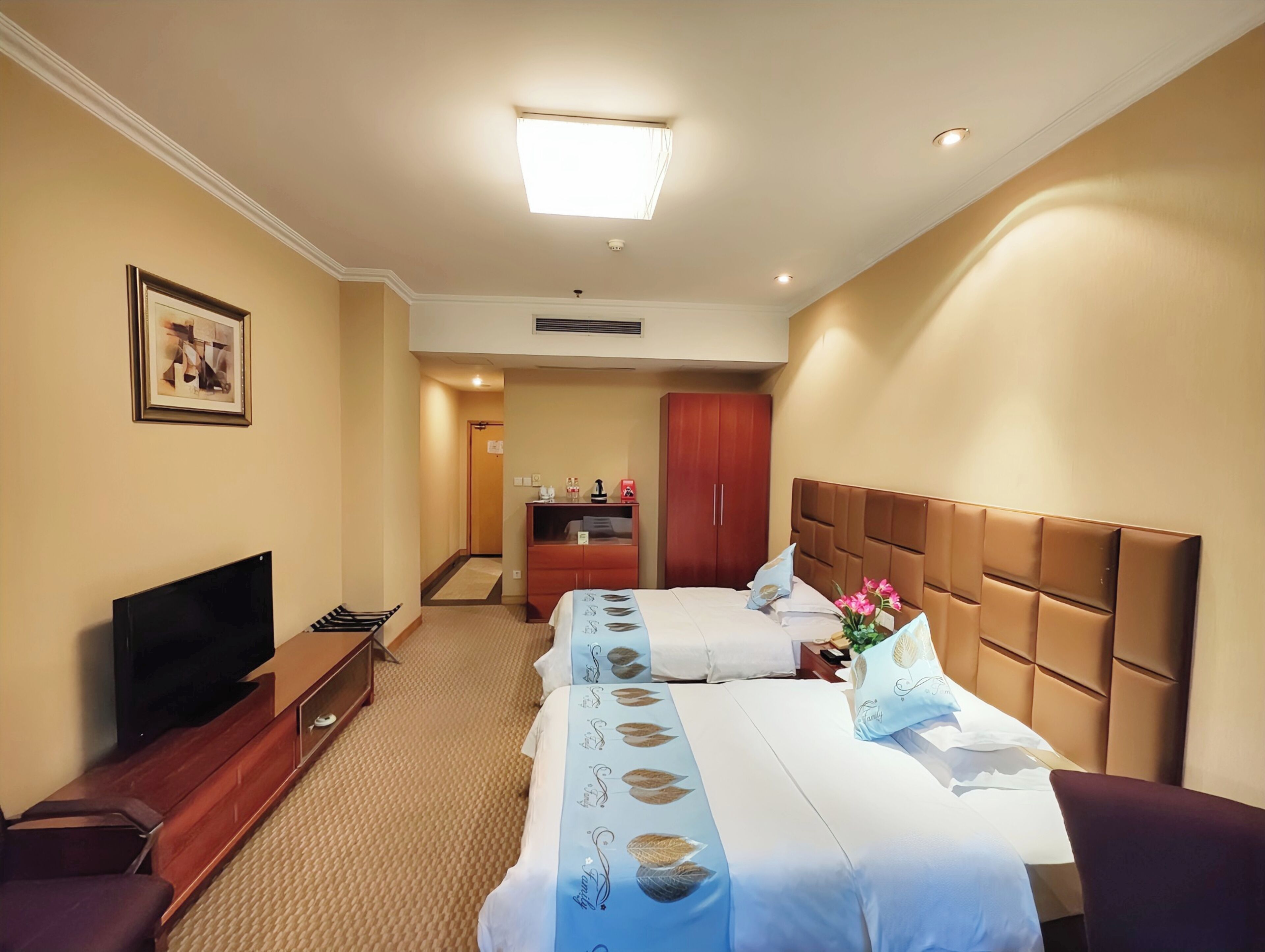 A hotel room with two beds, a TV, a desk, and a wardrobe.