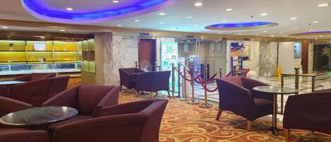 A hotel lobby with seating areas, a reception desk, and a jewelry display.