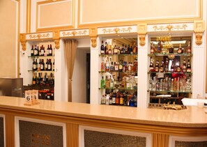 A bar area with shelves of liquor bottles, a counter, and a decorative curtain.