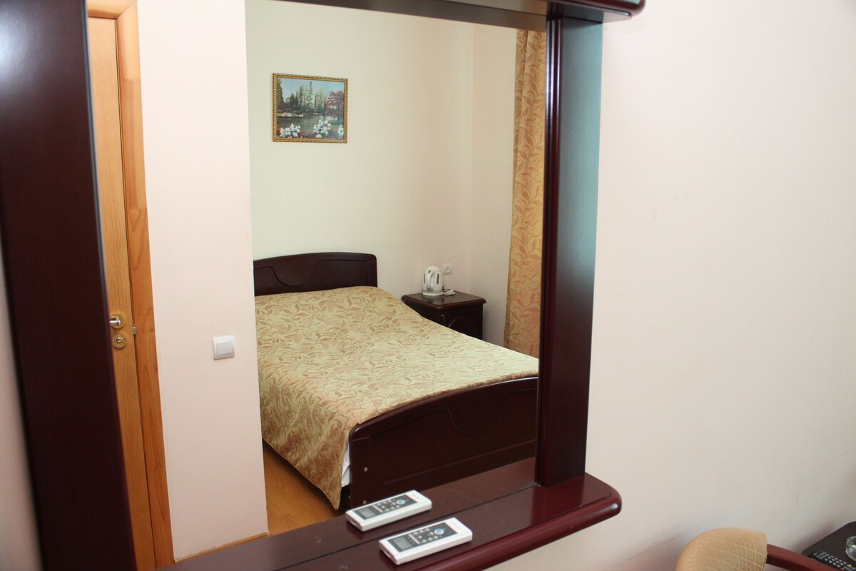 A bedroom with a bed, bedside table, and a mirror.