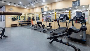 Une salle de sport équipée de tapis de course, d’appareils de musculation et d’un mur entièrement recouvert de miroirs.