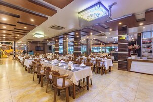 Um restaurante espaçoso com várias mesas e cadeiras, um balcão e uma grande janela com vista para o exterior.