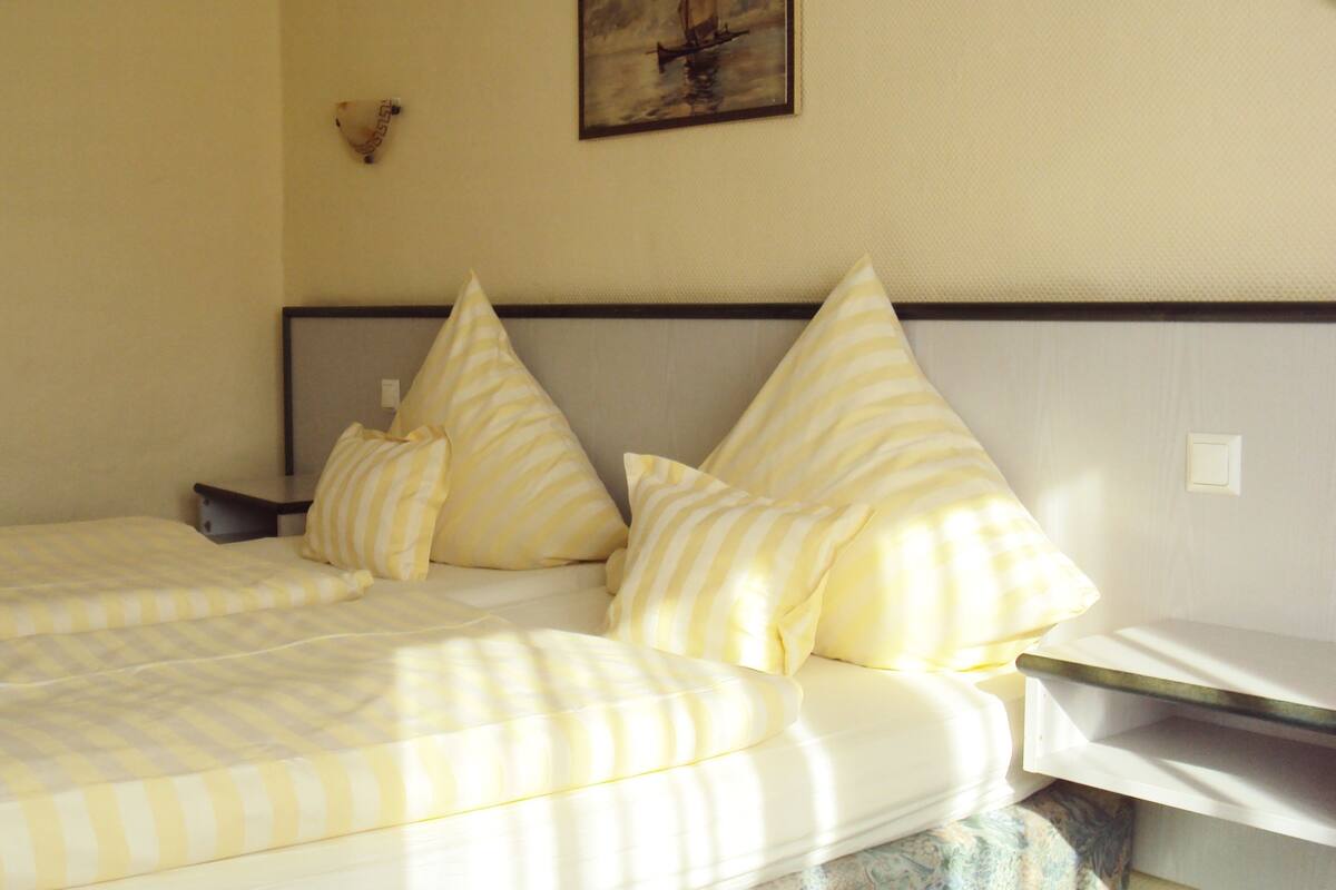 Une chambre d’hôtel avec un lit, des oreillers, une table de chevet et un tableau au mur.