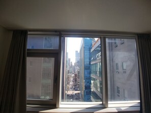 A view through a window with a cityscape, including modern buildings and a busy street.