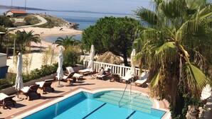A swimming pool with lounge chairs and umbrellas, surrounded by greenery and a view of the sea. - Villa Kastel (Povljana)
