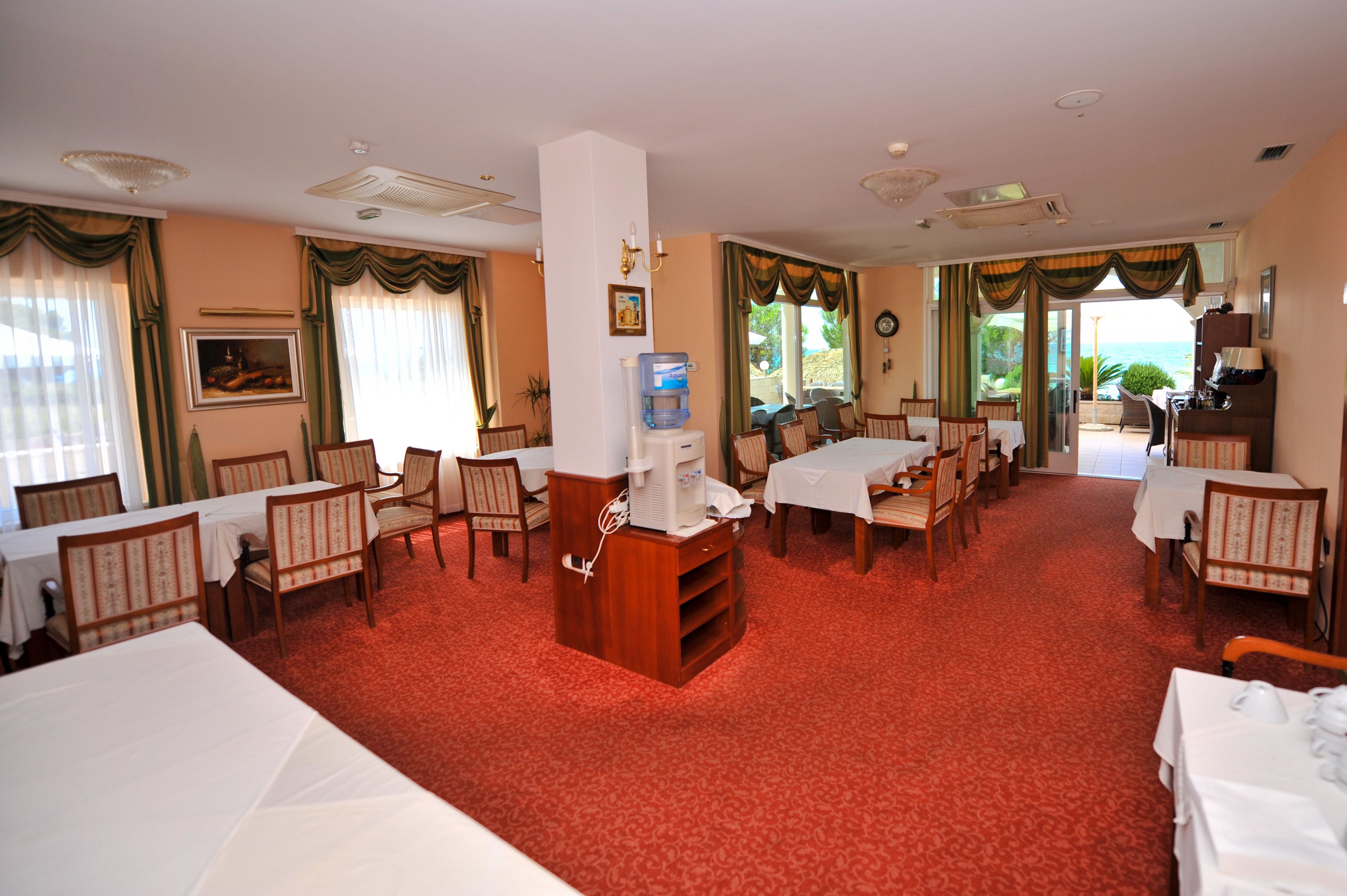 A hotel room with multiple beds, a minibar, a television, and a view of the outdoors.