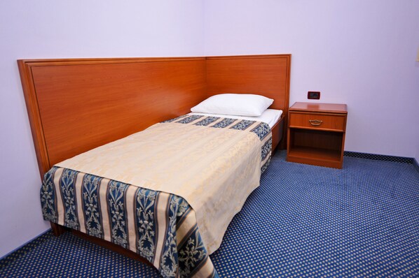 A neatly made bed with a patterned bedspread and a wooden headboard.