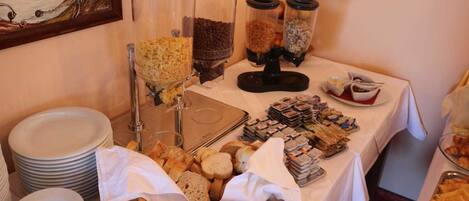 Una mesa de buffet con diferentes alimentos, como pan, pasteles y salsas.