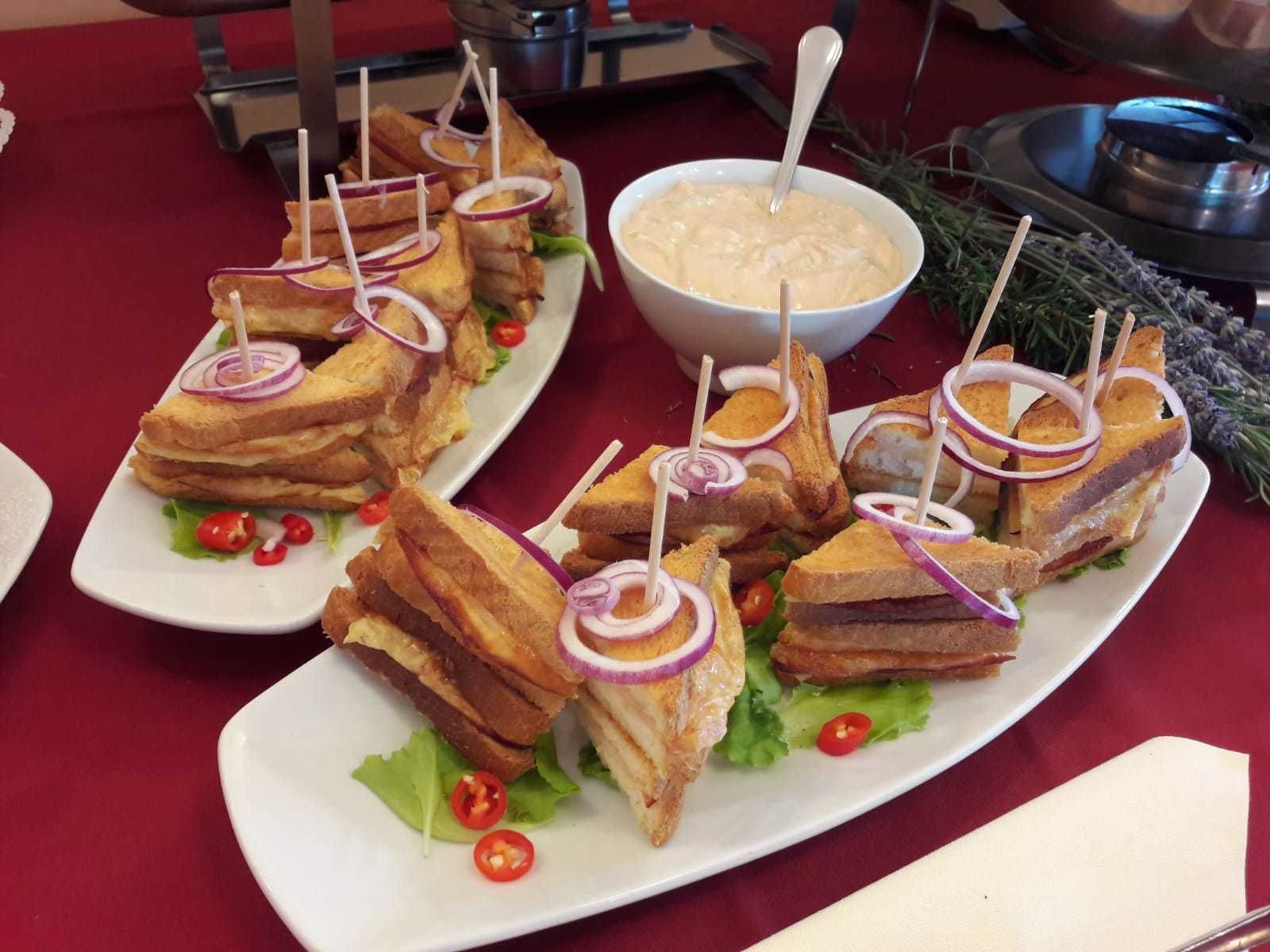 Une table de buffet avec des assiettes de sandwichs, un bol de trempette et des accompagnements.