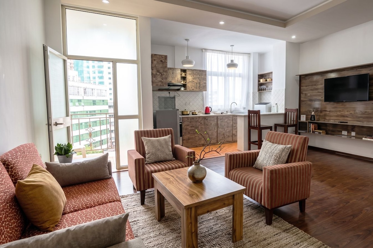 Un salon moderne comprenant un canapé, des fauteuils, une table basse et un téléviseur.