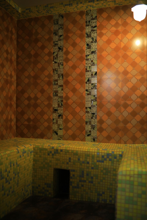 A room with patterned walls and a tiled floor, featuring a small alcove with a door.