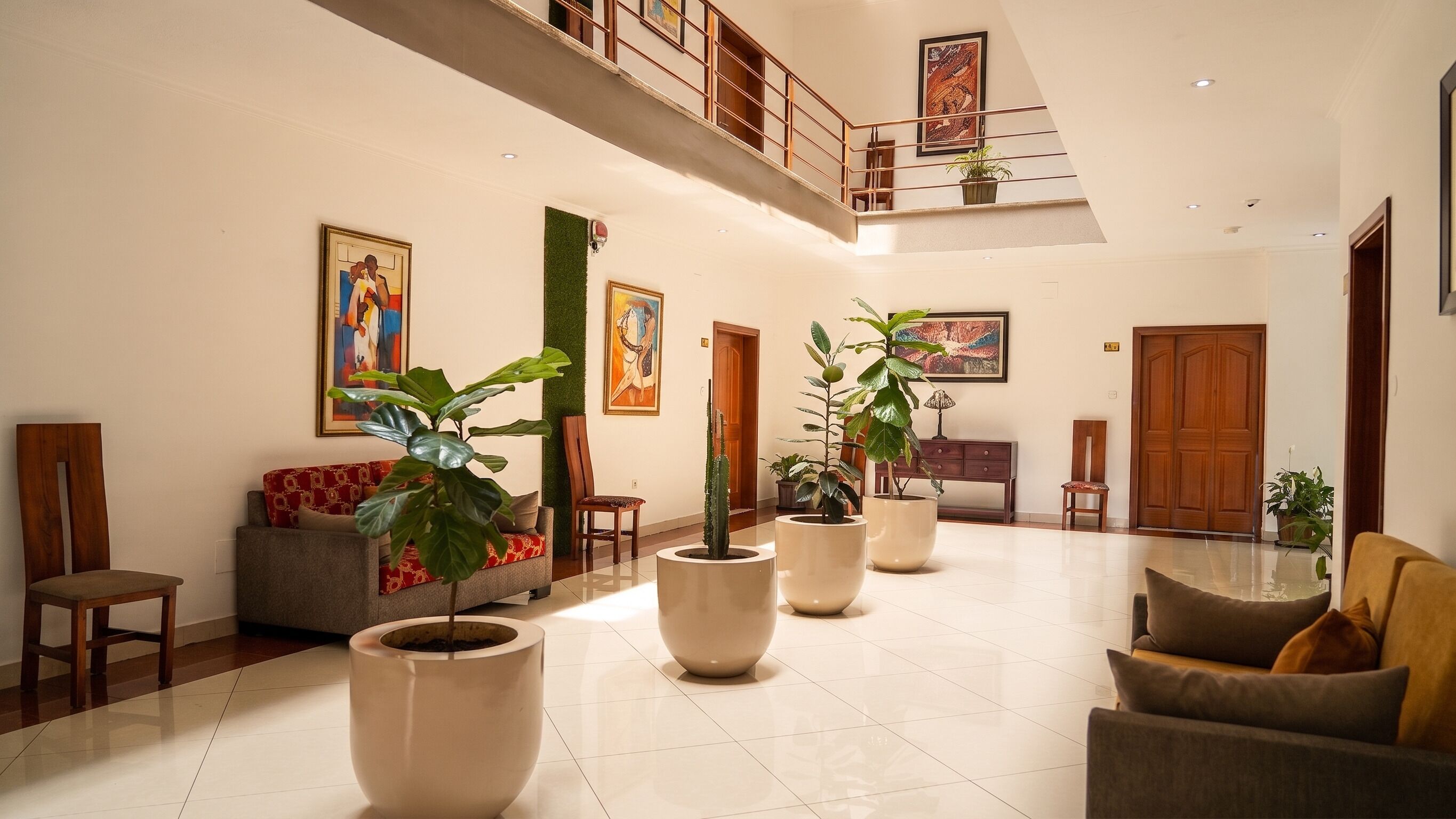 A spacious lobby with a high ceiling, a staircase, and multiple seating areas.