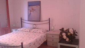 A bedroom with a bed, a nightstand, a lamp, and a framed picture on the wall. - L'Onda Blu (Domus de Maria)