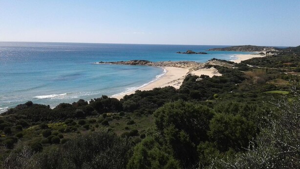 A coastal landscape with a sandy beach, dense greenery, and rocky outcrops. - L'Onda Blu (Domus de Maria)
