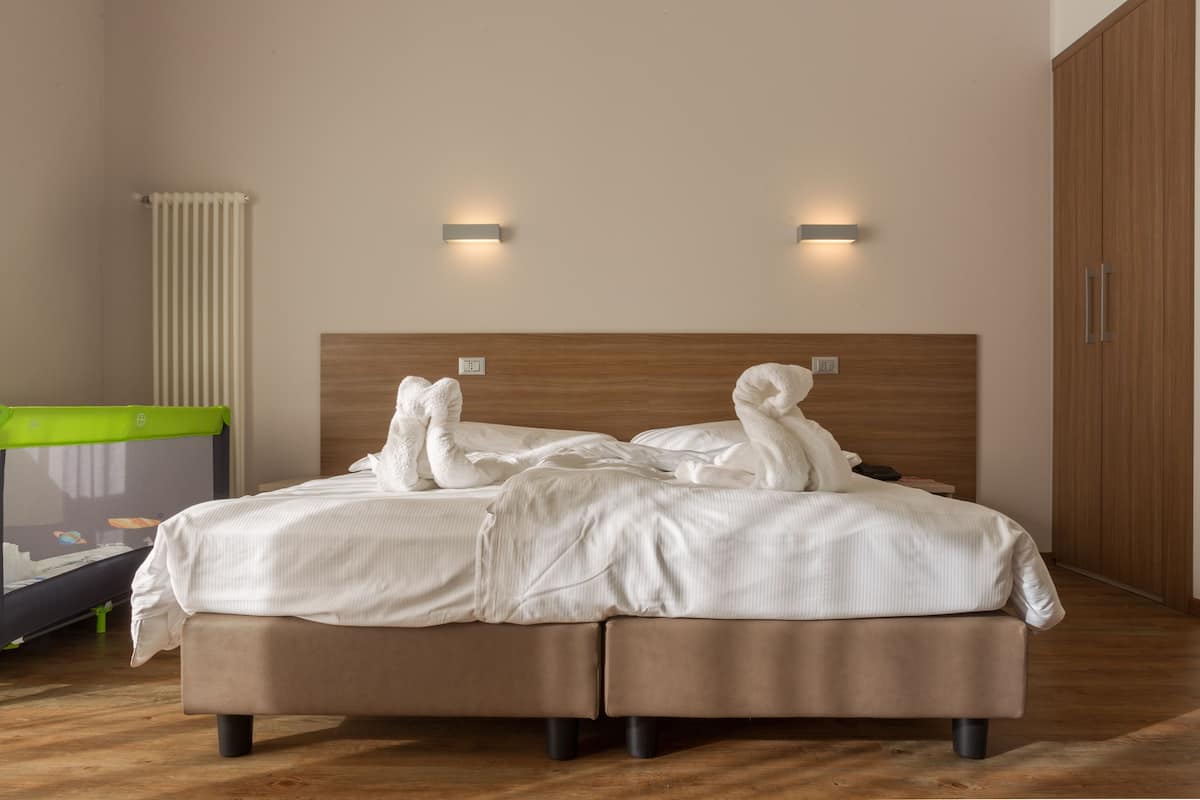 A double bed with a wooden headboard, two wall-mounted lights, and a radiator.