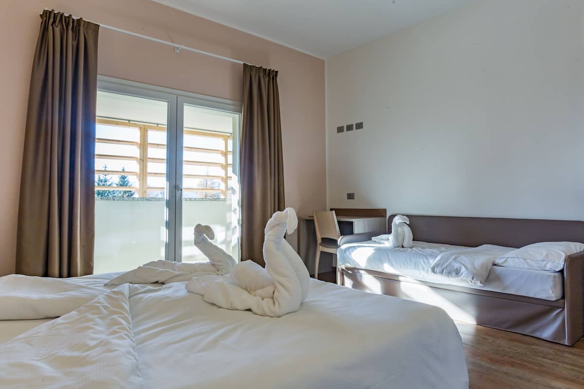 A hotel room with a large bed, a smaller bed, and a desk.