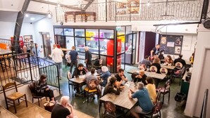 A spacious indoor dining area with multiple tables and chairs, a staircase, and a view of the street outside. - Cinema Hostel Jerusalem (Jerusalem)