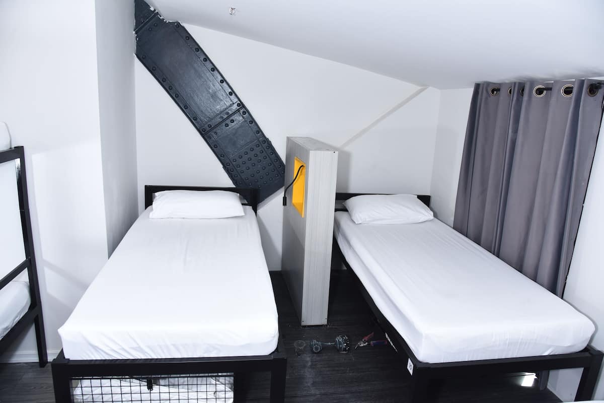 A compact room with two single beds, a small table, and a chair.