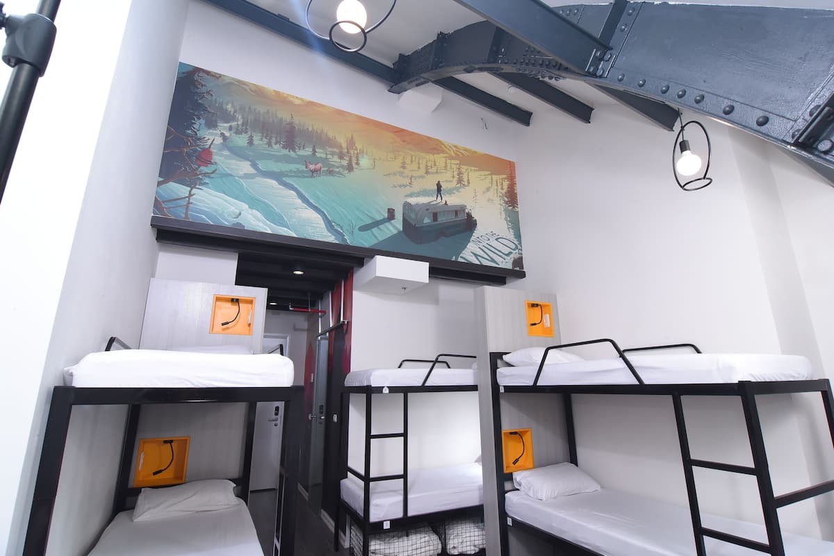 A room with bunk beds, a painting of a snowy landscape, and a door leading to another area.