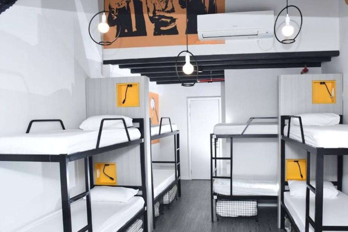 A dormitory room with bunk beds, a whiteboard, and a clock on the wall.