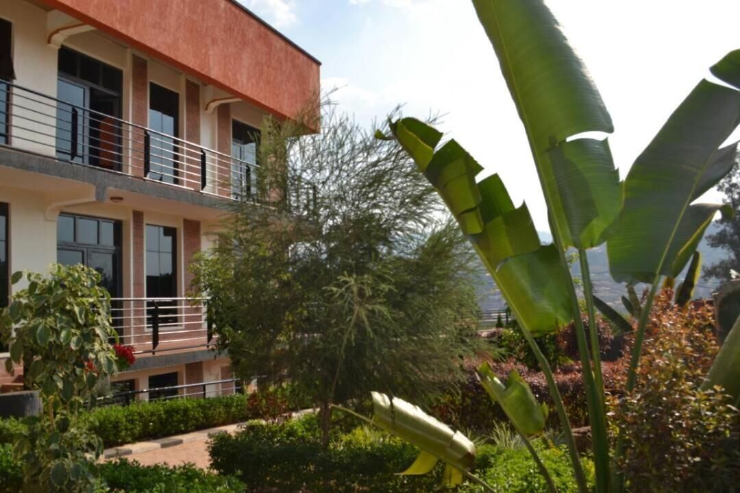 A multi-story building with balconies, surrounded by lush greenery and a variety of plants.