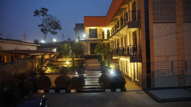 A modern hotel with a well-lit entrance, a staircase leading to the upper floors, and a landscaped garden area. - Shami Luxury Apart (Kigali)