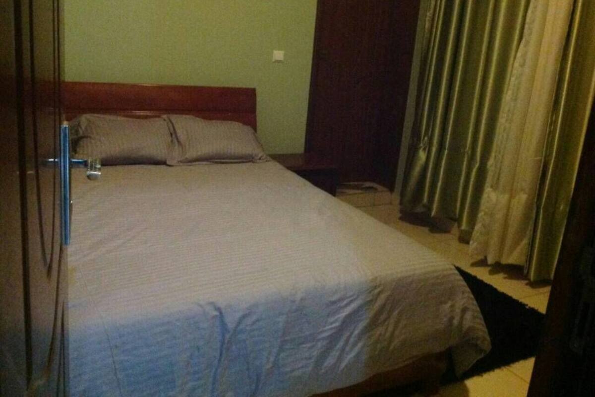 Une chambre à coucher avec un lit, une table de chevet et un rideau.