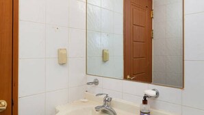 A bathroom with a white sink, a mirror, and a wooden door.