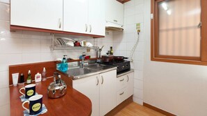 A compact kitchen with white cabinets, a stainless steel sink, and a stove.