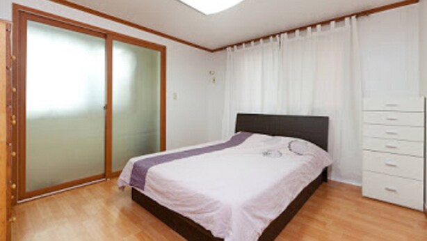 A bedroom with a bed, a wardrobe, a sliding glass door, and a ceiling light.