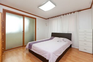 Un dormitorio con cama, armario, puerta corrediza de vidrio y lámpara en el techo.