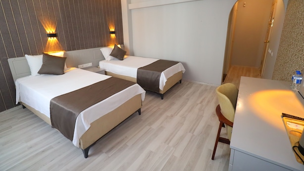 A hotel room with two beds, a desk, and a chair. - Artan Hotel (Isparta)