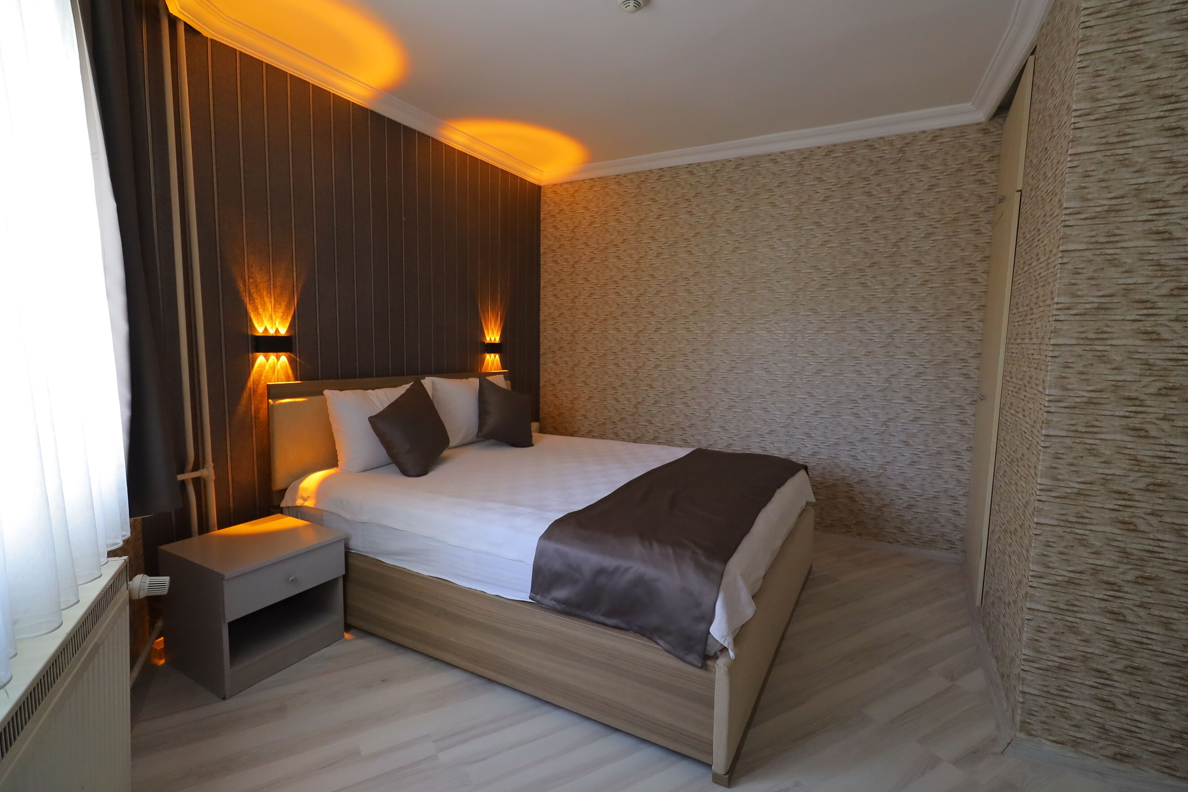 A modern bedroom with a wooden bed, nightstands, and wall-mounted lamps.