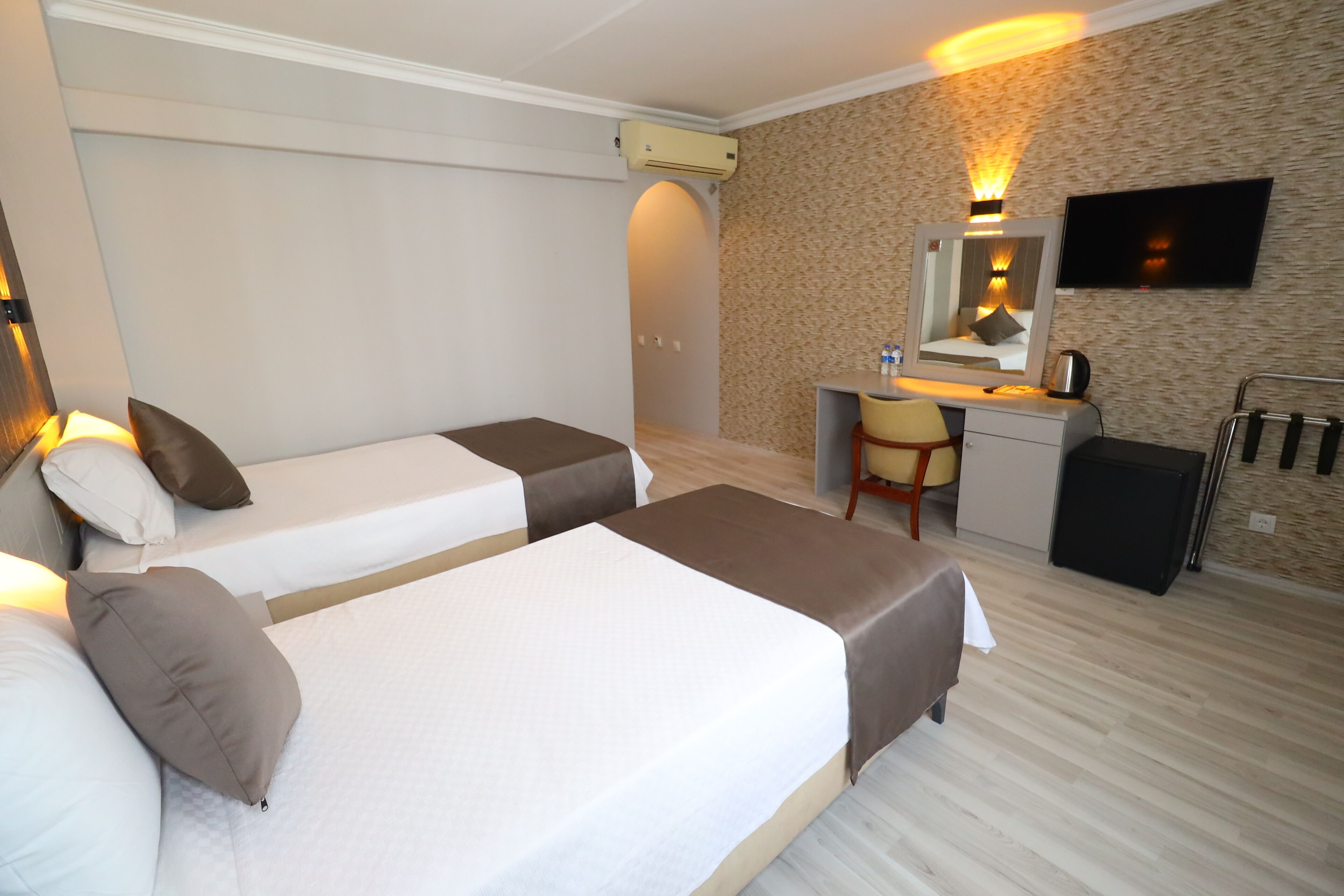 A hotel room with two single beds, a desk with a chair, a television, and a mirror.