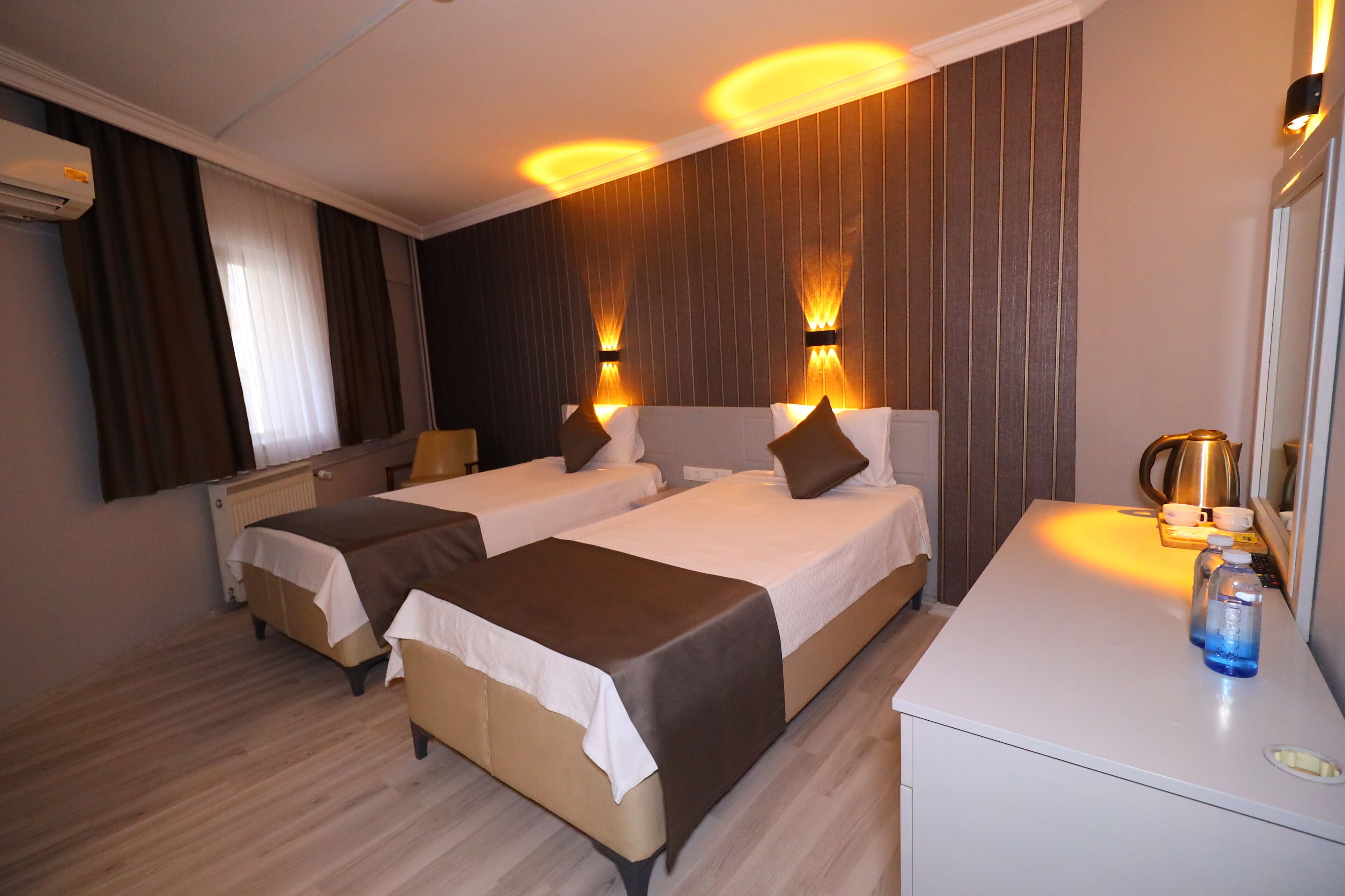Una habitación de hotel con dos camas, un escritorio y un espejo.
