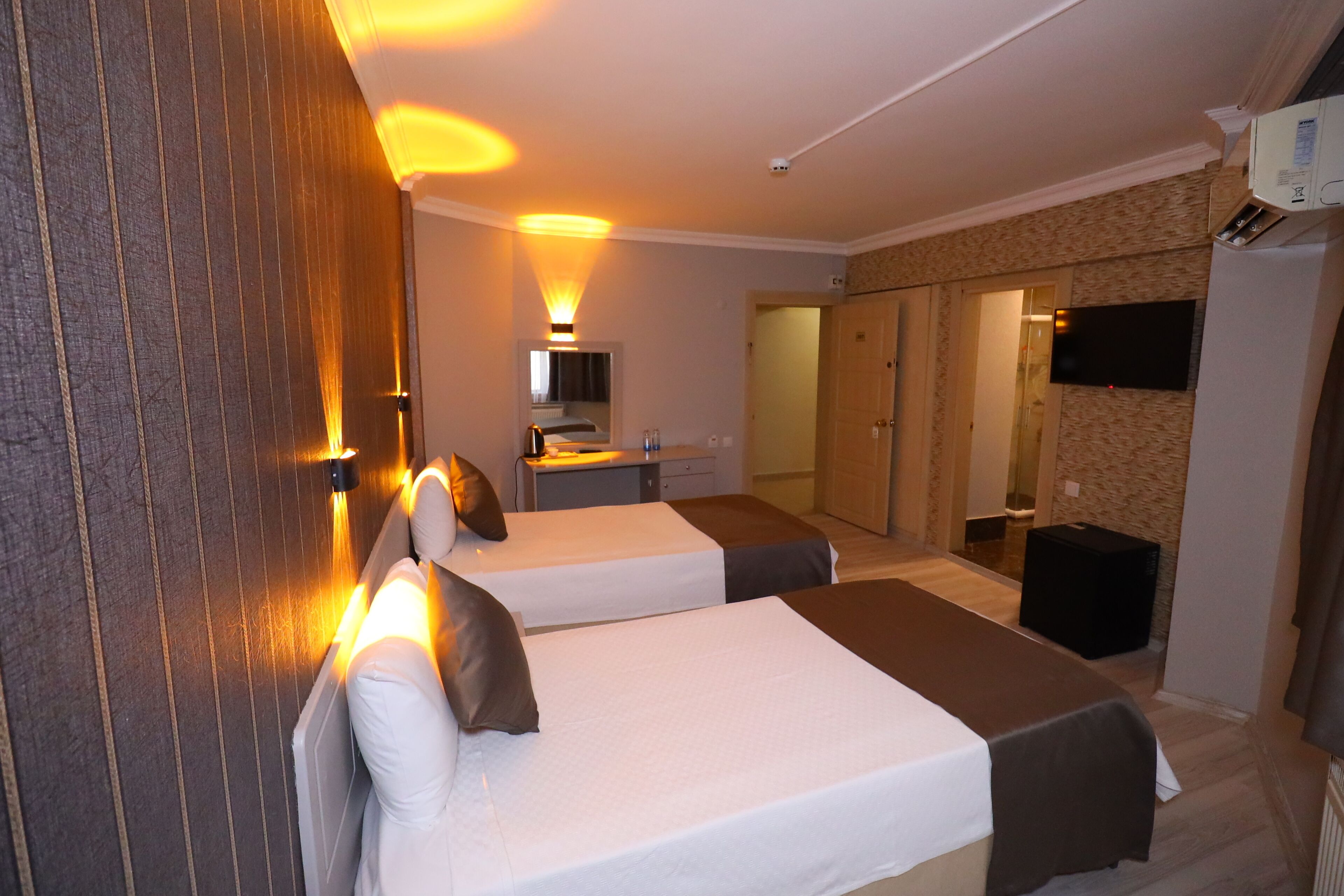 Een hotelkamer met twee bedden, een bureau, een spiegel, een televisie en een kledingkast.