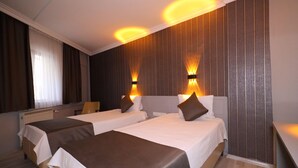 A hotel room with two beds, a large mirror, and wall-mounted lighting. - Artan Hotel (Isparta)