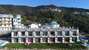 A multi-story hotel with balconies, a green lawn, and a mountainous backdrop. - Mountain View Resort (Kandaghat)