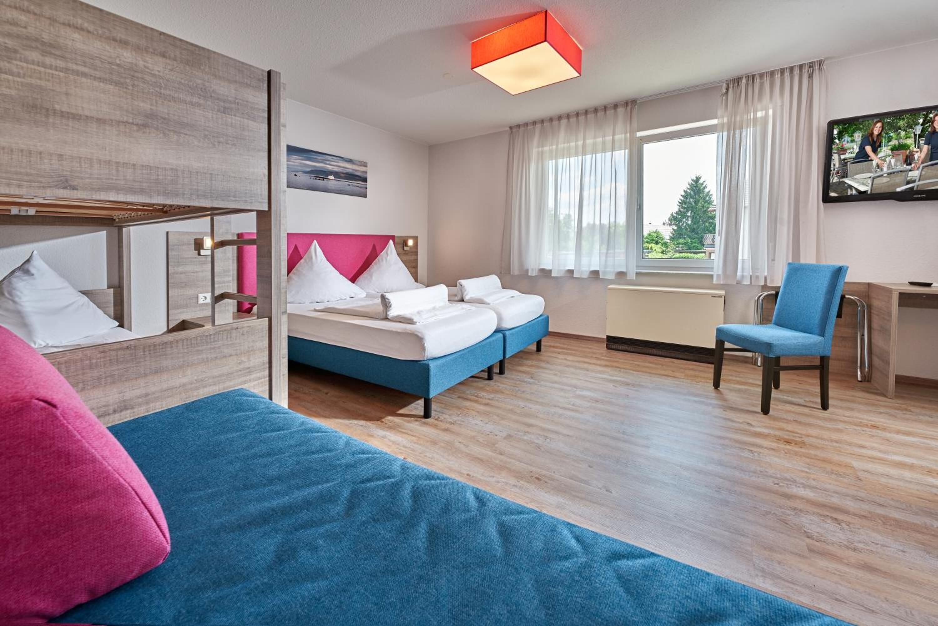 A modern hotel room with a large bed, a desk, and a TV.
