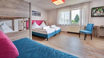 A modern hotel room with a large bed, a desk, and a TV.