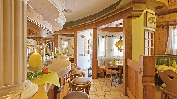 A cozy restaurant with wooden furniture, a bar area, and a dining section. - Gästehaus Mythos (Rust)