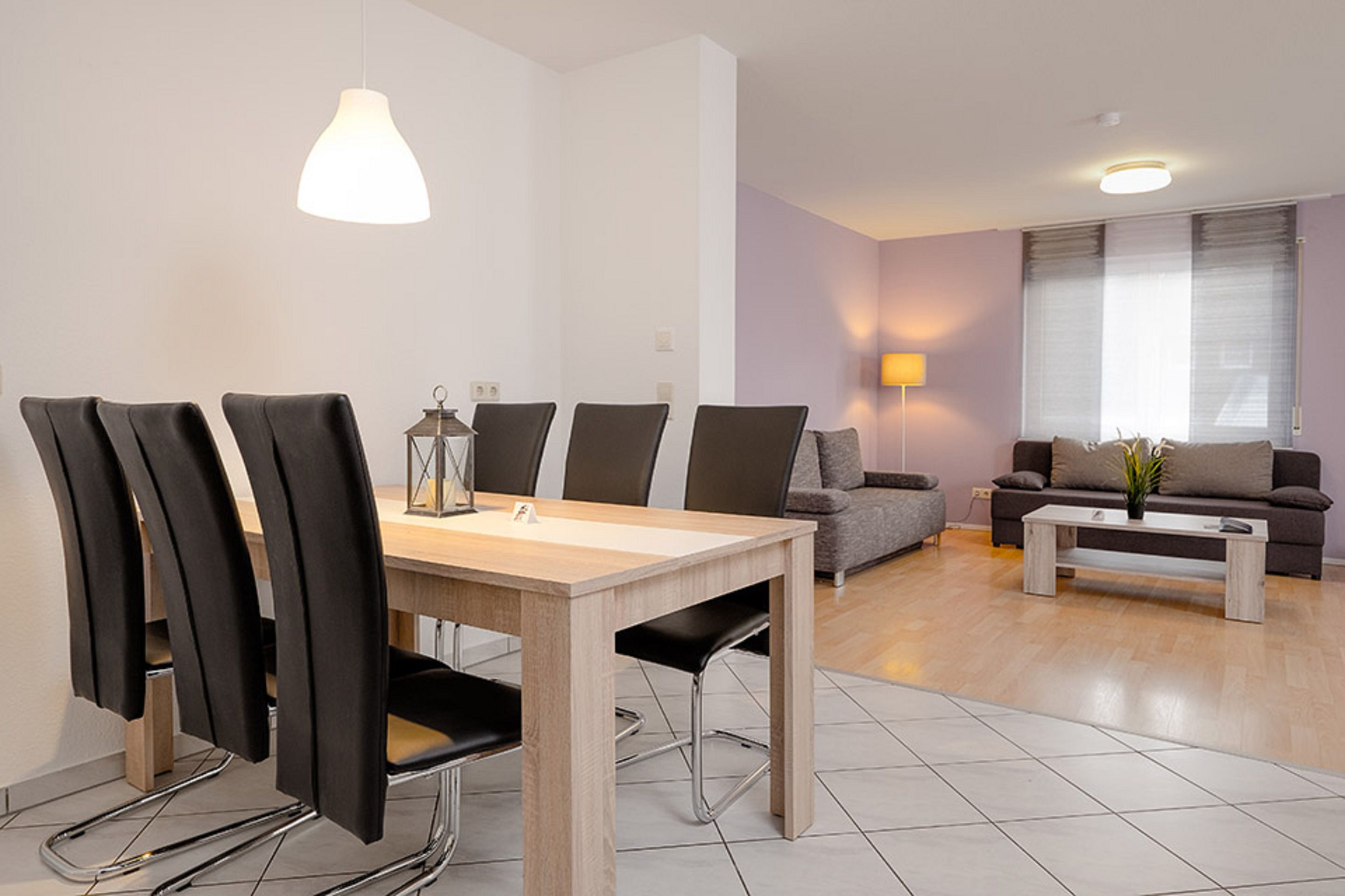 A modern living room with a dining table, chairs, a sofa, and a coffee table.