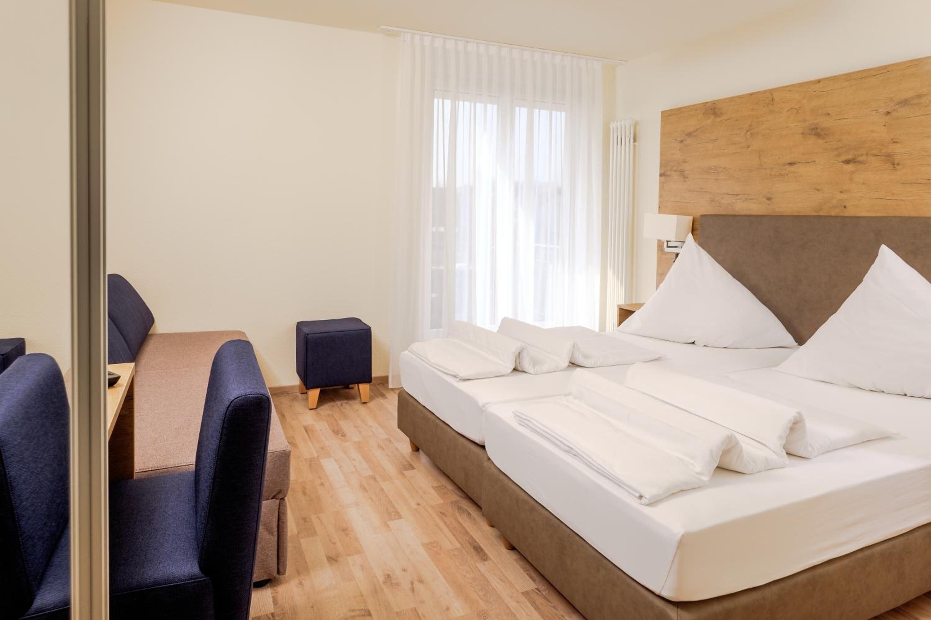 A hotel room with a bed, a desk, and a chair.