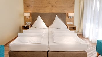 Ein Doppelbett mit Holzvorhang, Nachttische mit Lampen und Blick ins Freie durch transparente Vorhänge.
