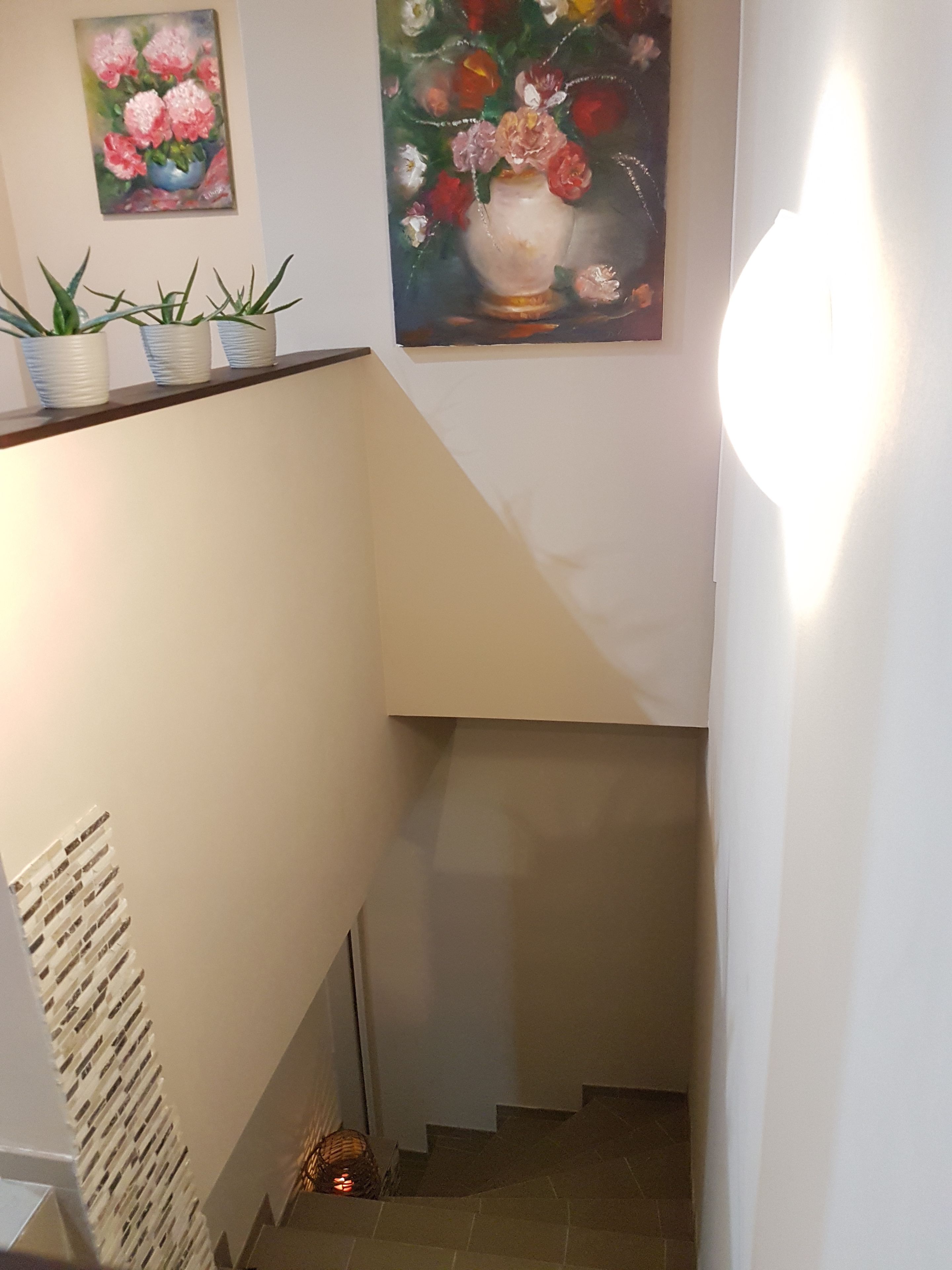 A staircase with a white wall and a painting of flowers.