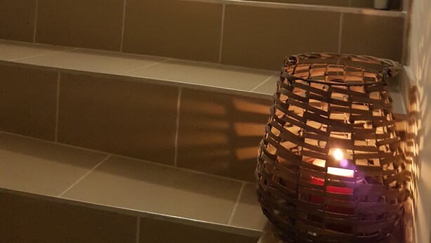 A staircase with beige tiles and a woven basket with a light source inside. - Hédi Vendégház (Eger)