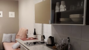 A compact kitchen with a sink, a kettle, and a coffee maker. There is a dining area with a table and chairs. - Hédi Vendégház (Eger)