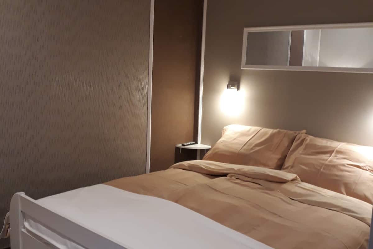 A neatly made bed with a white headboard and a beige blanket.