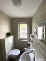 Un baño pequeño y funcional con inodoro, lavamanos y una ventana.