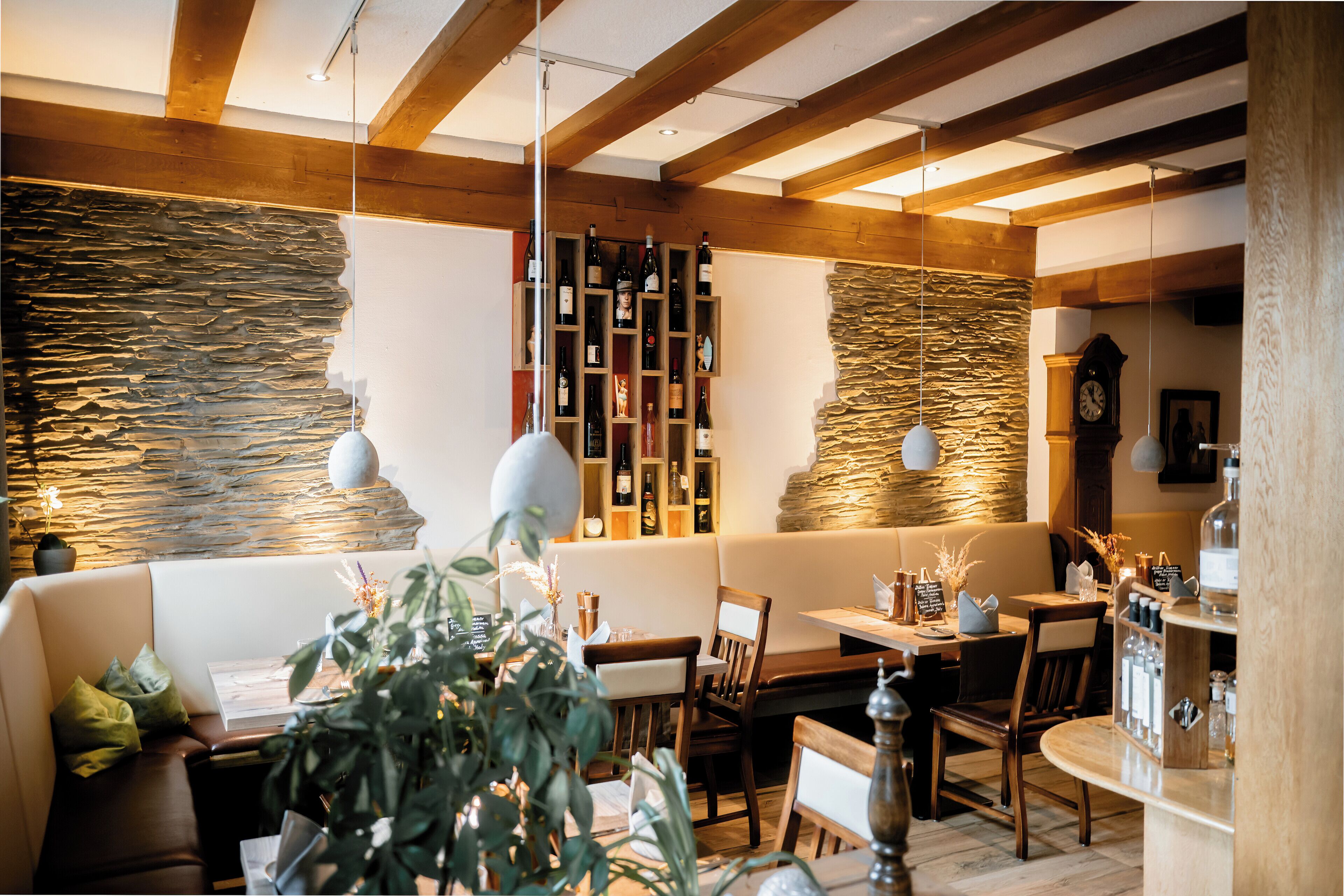 En mysig restaurang med träbjälkar, stenmurar och olika typer av sittplatser, inklusive en bänk och bord.